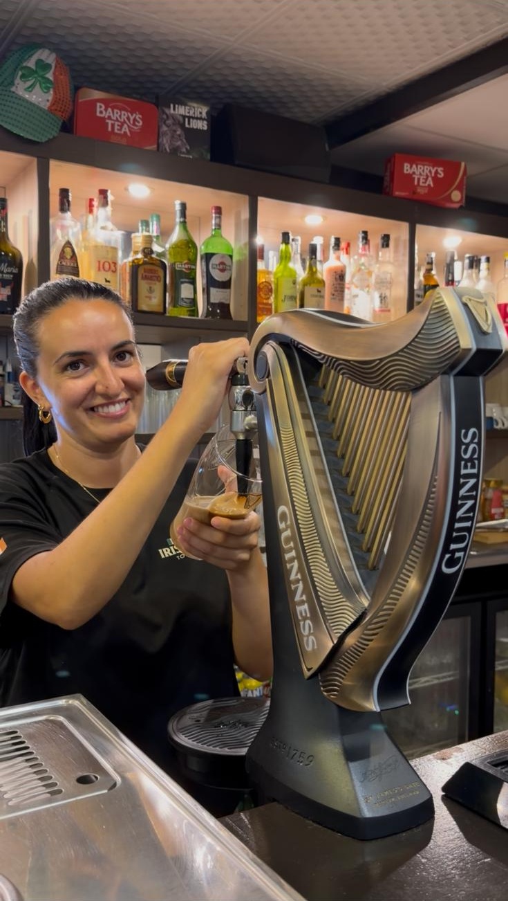 Sarah pouring a pint of Guinness behind the bar